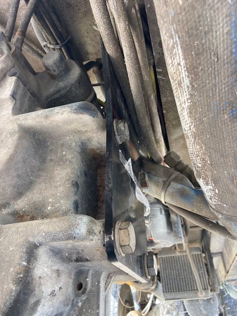 Black metal bracket bolted to a textured gray surface with hoses and wires.