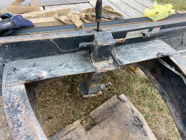Black trailer hitch assembly with a lever on a flatbed trailer.