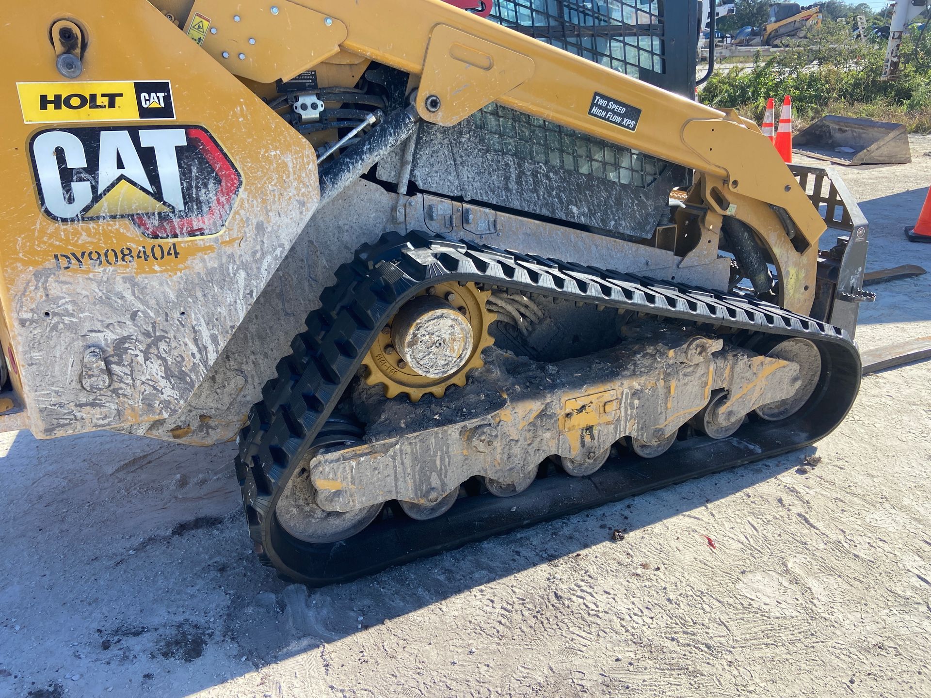 Yellow Caterpillar skid steer loader with dirt on tracks and body. 