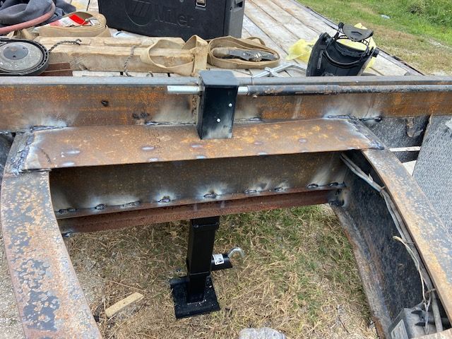 Welded metal frame with a black support jack; outdoor setting.