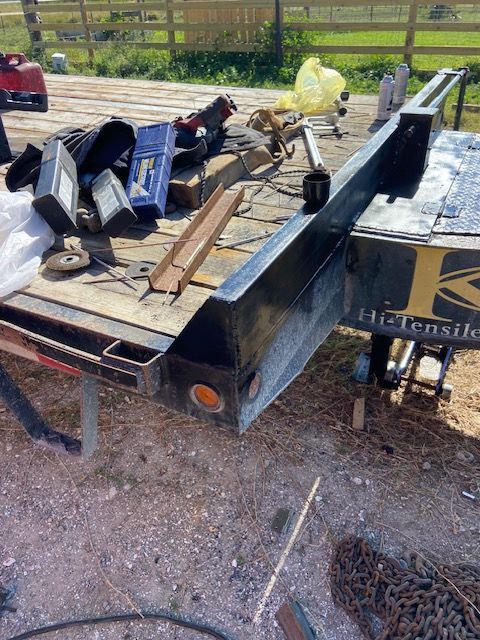 Black trailer bed with tools scattered on top, sunny outdoor setting.
