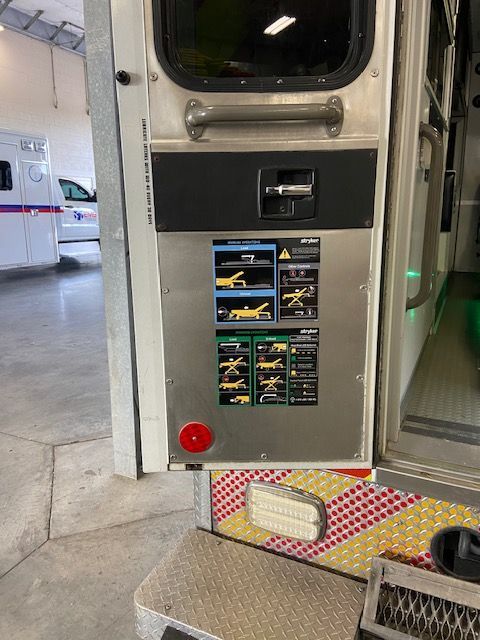 Rear of ambulance with stainless steel panel. Diagrams with instructions. Red button below.