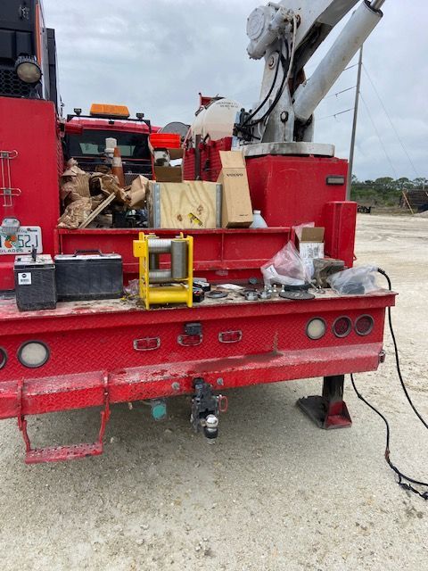 Red utility truck bed with equipment, tools, and a winch, outdoors.