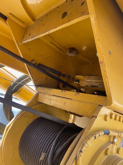 Yellow crane machinery with steel cables and a cable spool.