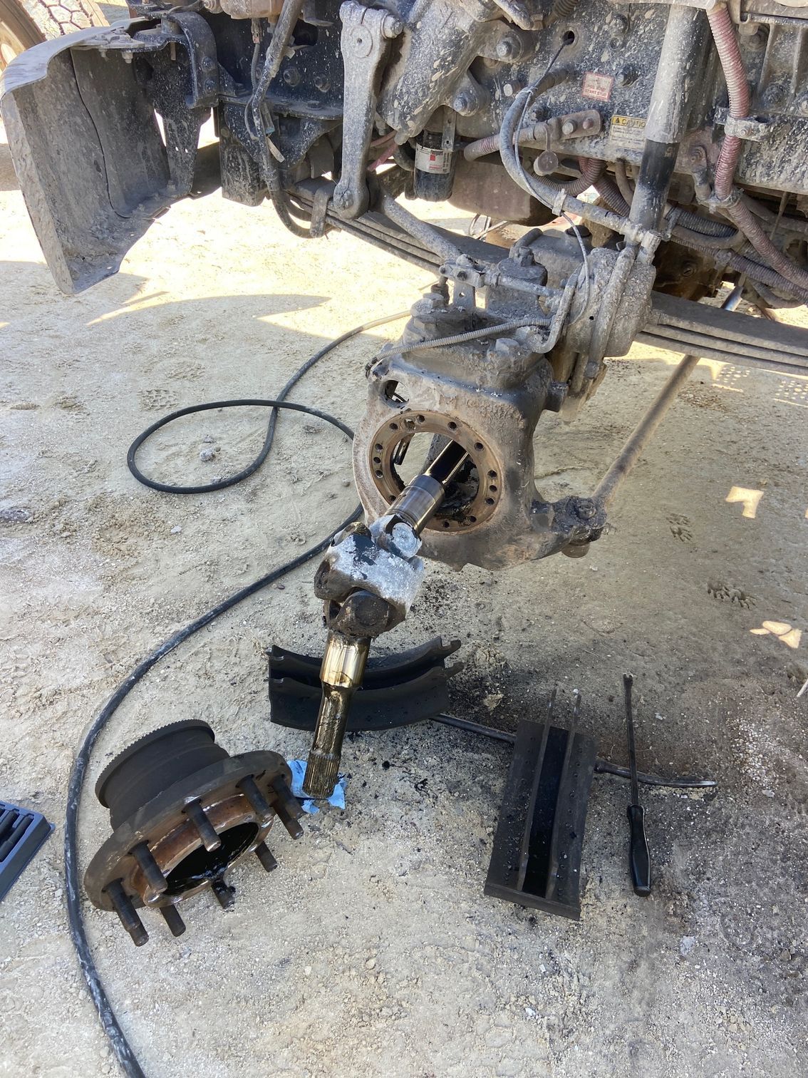 Truck axle assembly disassembled outdoors with parts laid out.