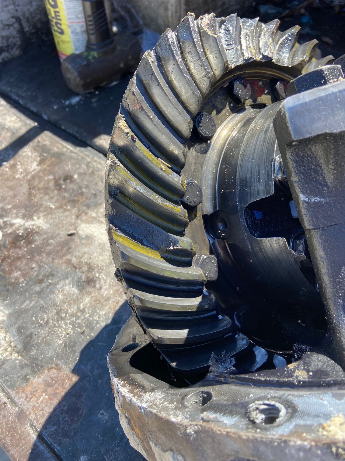 Close-up of a damaged gear assembly with broken teeth and oil.