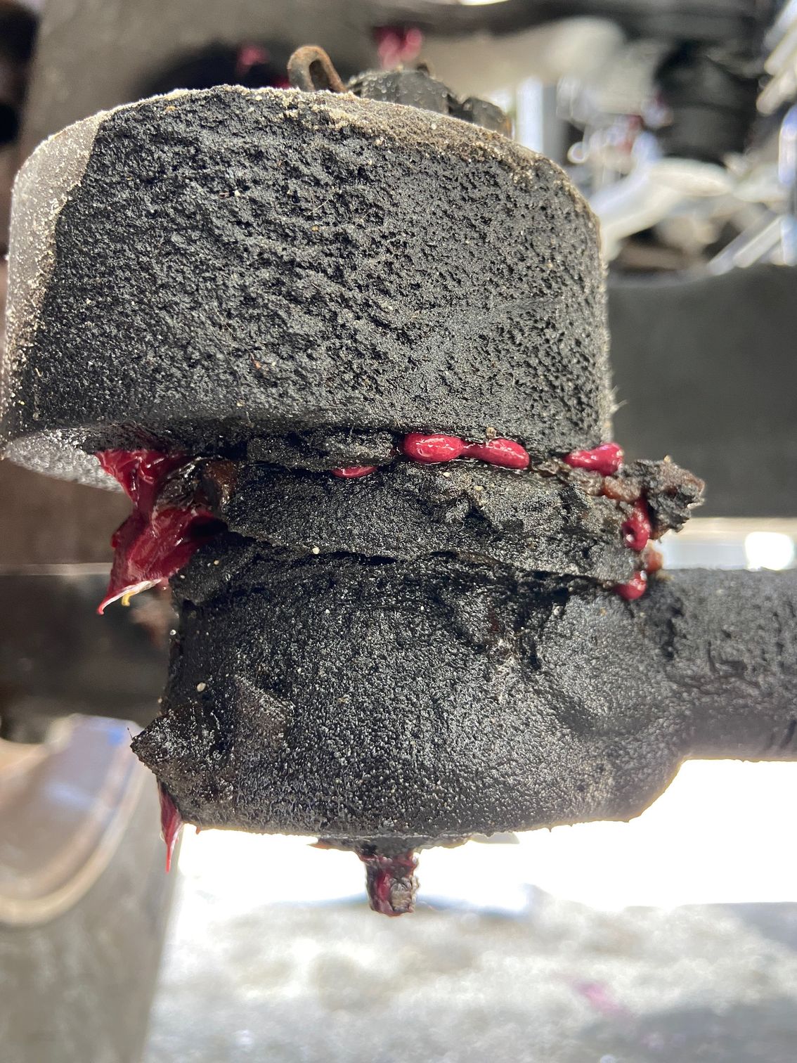 Grease-covered ball joint with pink lubricant. Appears to be on a vehicle.