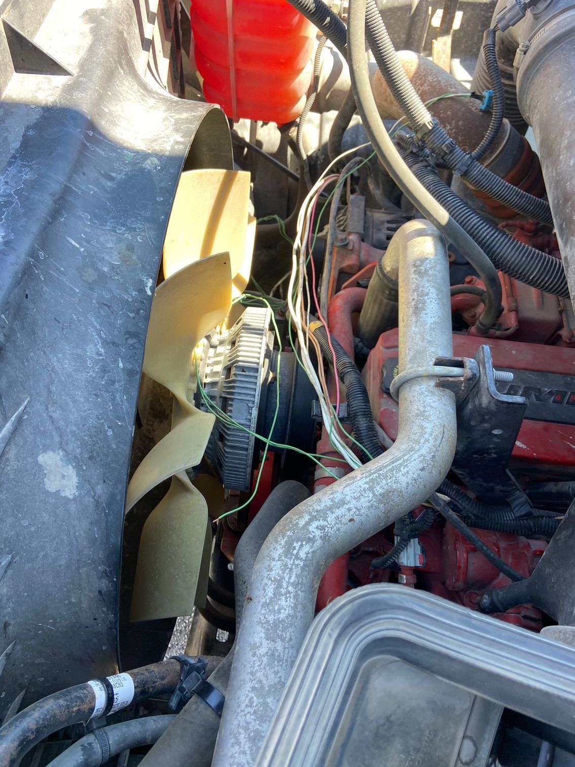 Engine bay with fan, wiring, and coolant reservoir.