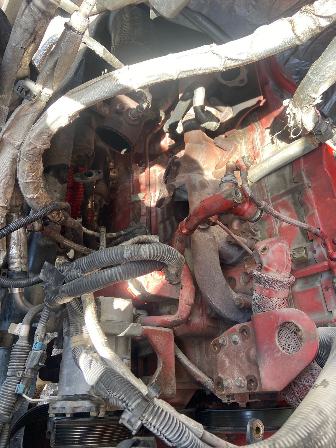 Red truck engine, hoses, and wiring visible. Interior view with a narrow, central space.