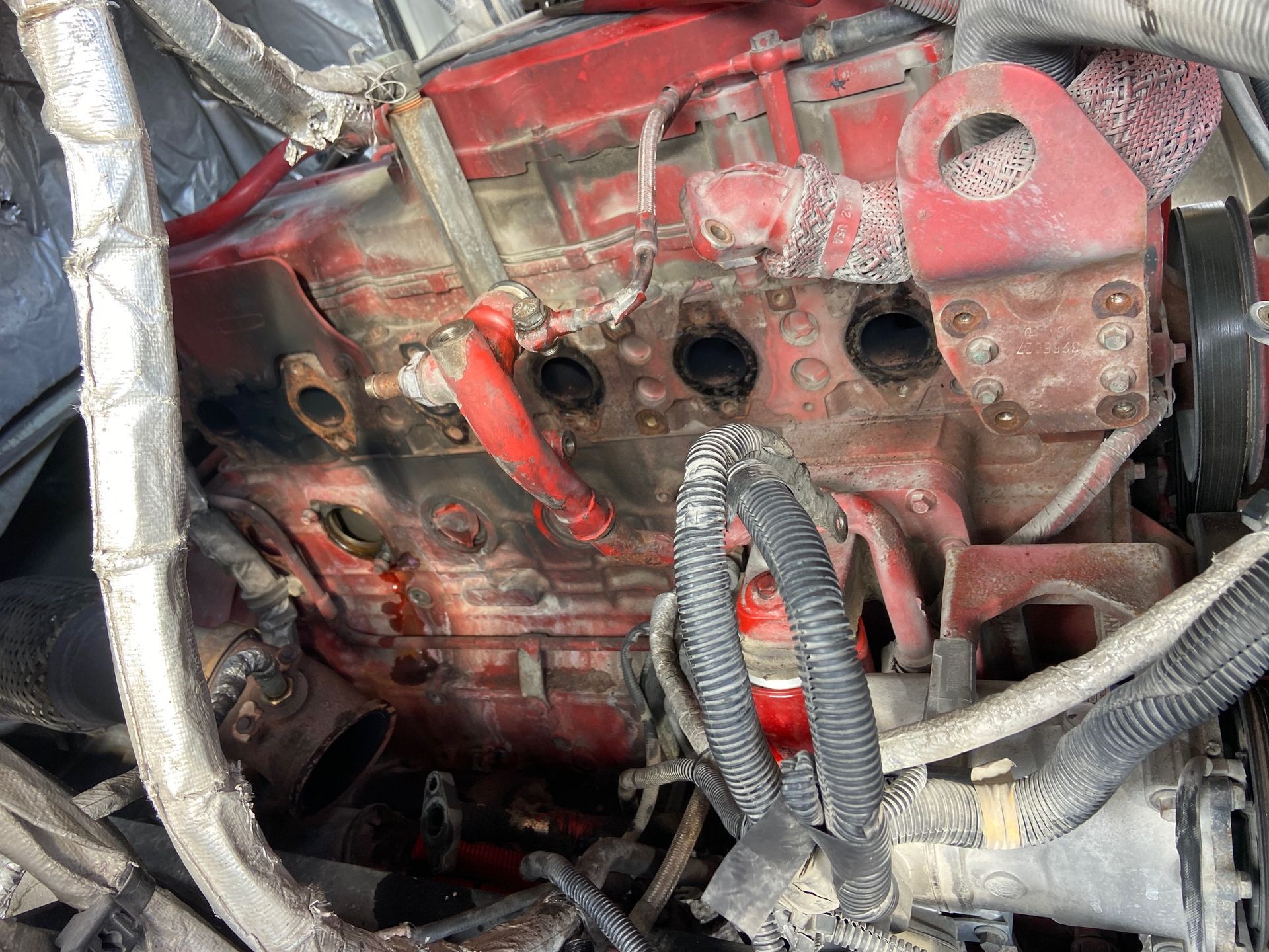 Close-up of a dusty red engine with multiple holes and tubing.