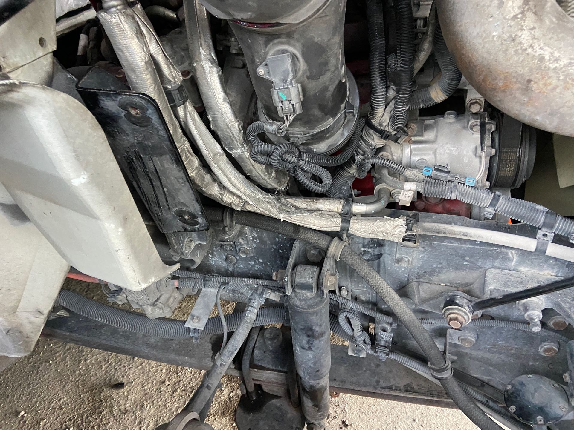 Truck engine, close-up view.  Black and silver parts. Various hoses and tubes are visible.
