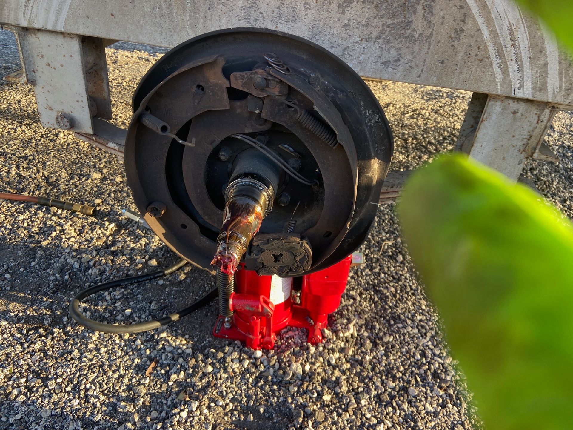 Trailer wheel assembly disassembled, showing brake components and axle with red jack.