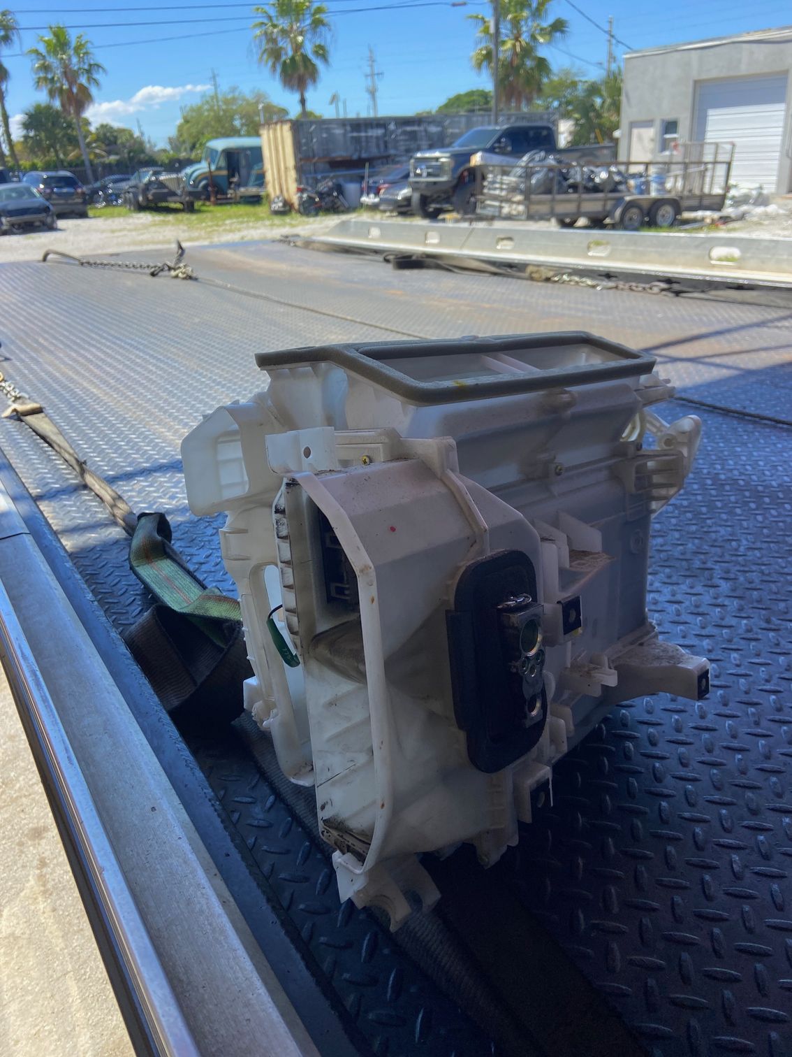 Air conditioning unit on a flatbed tow truck outdoors. Light-colored plastic, black controls, blue sky background.