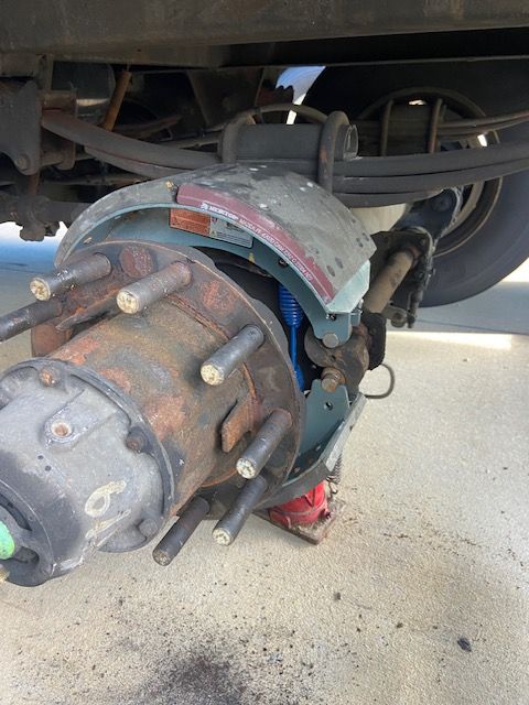 Close-up of a semi-truck wheel with brake components exposed. Rusty metal and blue details are visible.
