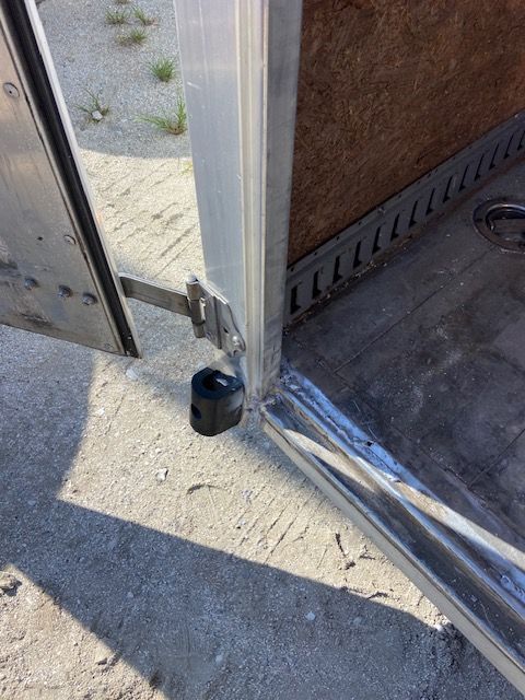 Open trailer door showing a black bumper and interior details, on a light-colored surface.