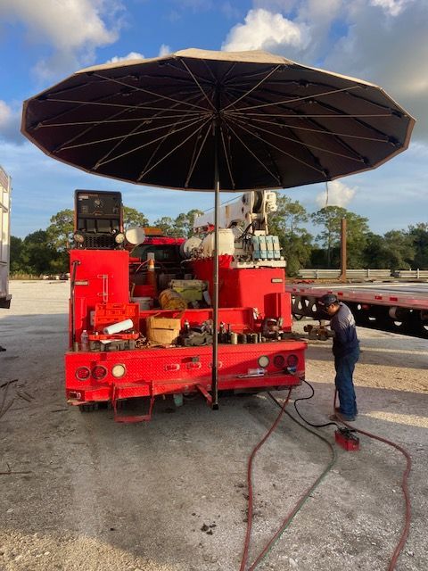 A red tow truck with a crane attached to it is parked in a parking lot.