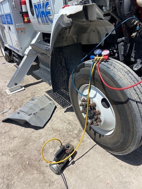 Truck with gauges attached to tire; pump on the ground.