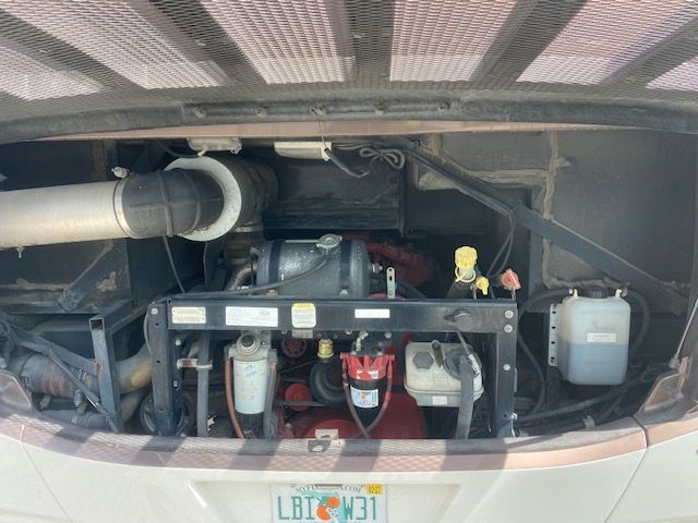 Open engine bay of an RV showing engine components, including filters, hoses, and fluid reservoirs.