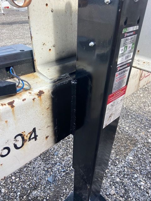 Black and white trailer jack assembly with rust and black paint.