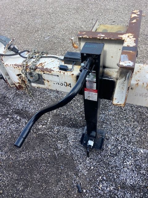 Trailer jack with crank handle, attached to white trailer hitch.