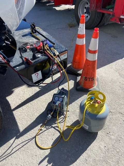 Refrigerant recovery equipment set up near a truck, with orange cones.