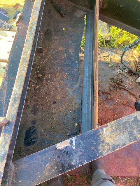 Rusting metal structure with a long metal beam inside. Outdoor setting.