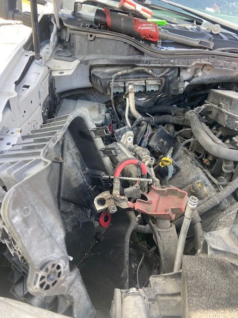 Open car engine bay with damage and tools.