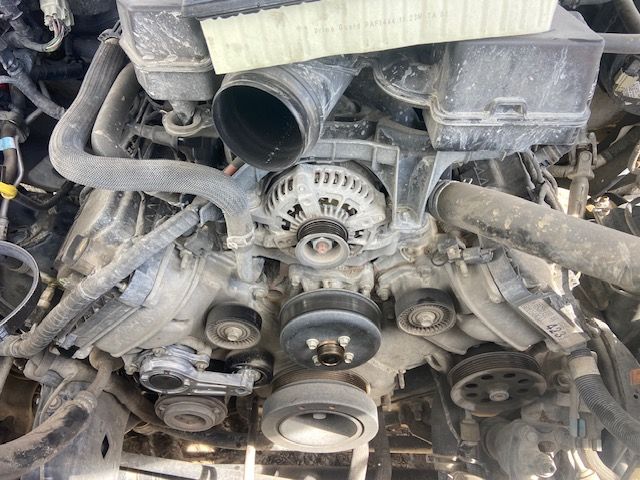 Overhead view of an engine showing pulleys, belt, alternator, and hoses.