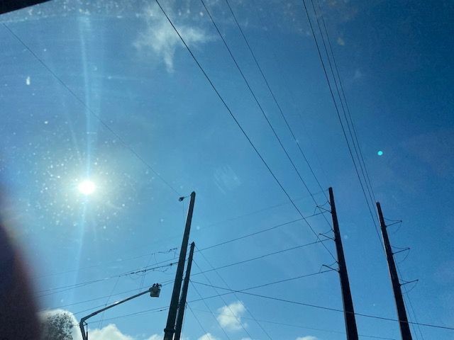 Bright blue sky with sun and utility poles.
