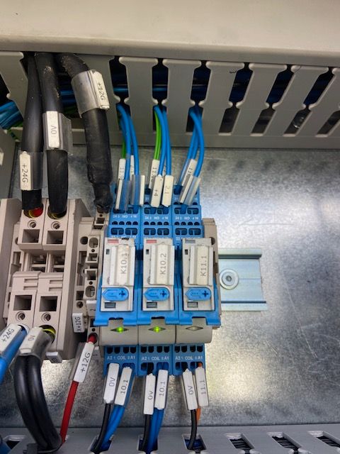 Electrical panel with blue circuit breakers and labeled wires.