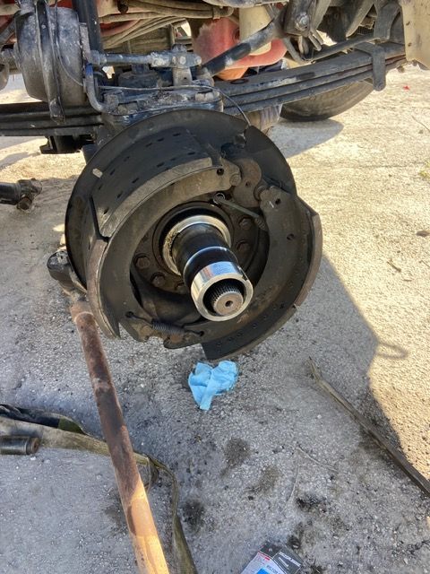 Truck rear wheel assembly, hub exposed, brake drum partially removed, on concrete.