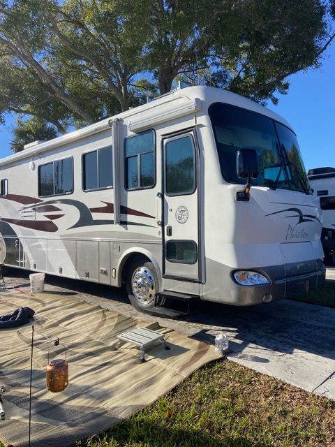 White and silver RV parked outside on a sunny day.