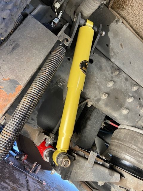 Yellow shock absorber mounted on a truck chassis.