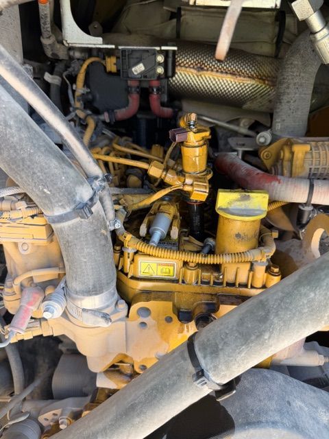 Yellow Caterpillar engine with hoses and components visible.