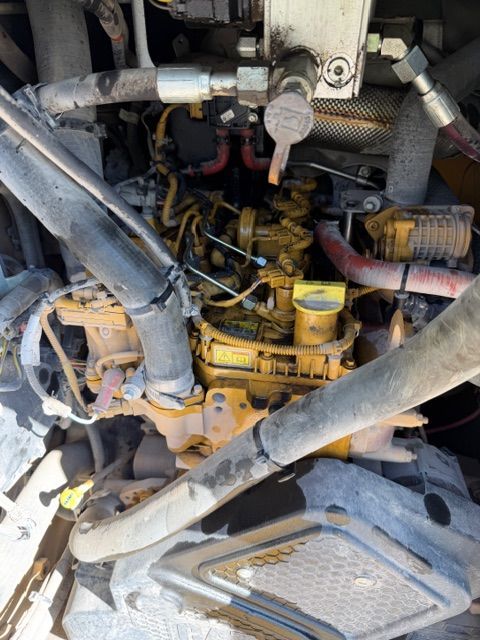 Yellow Caterpillar engine in an industrial setting, with various hoses and components.
