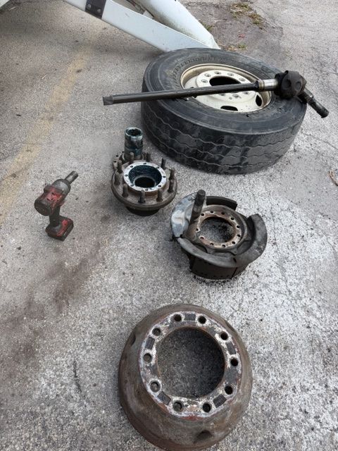 Scattered rusty metal wheel hub parts and a tire on concrete pavement