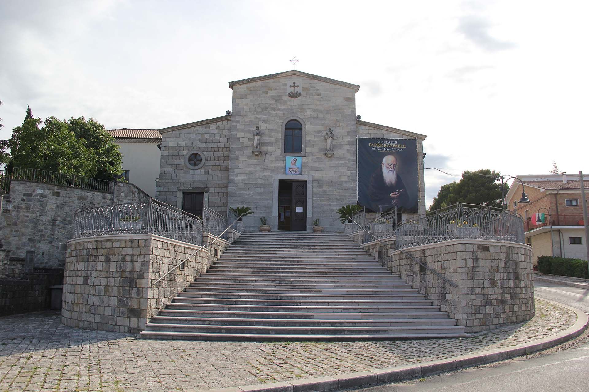 Chiesa in pietra con gradini che conducono all'ingresso, stendardo con un volto sul lato destro.