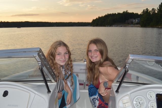 Two young girls are sitting on a boat in the water