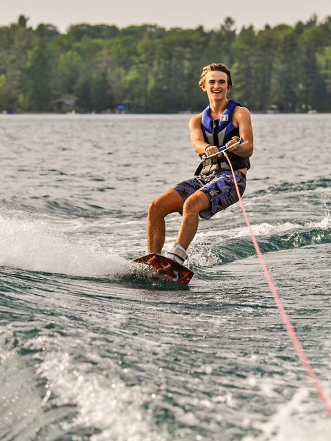 A man is water skiing on a lake with trees in the background.