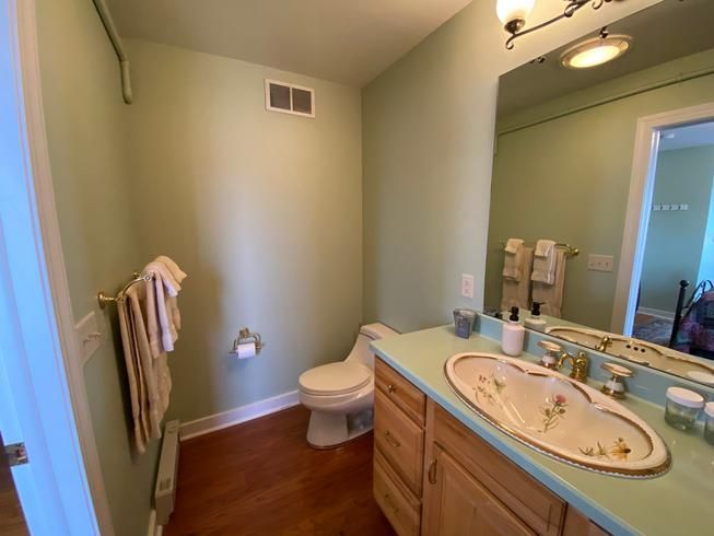 A bathroom with a toilet , sink and mirror.