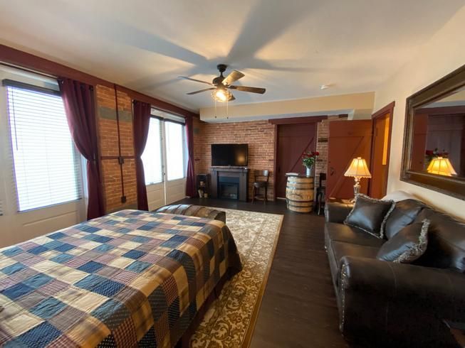 A bedroom with a bed , couch , television and a ceiling fan.