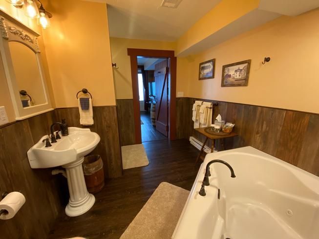 A bathroom with a jacuzzi tub , sink and mirror.