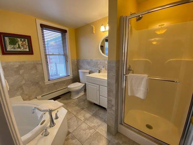 A bathroom with a tub , toilet , sink and shower.