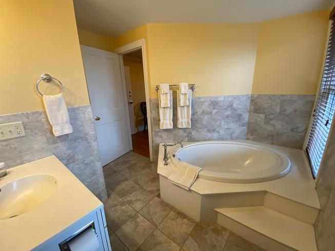 A bathroom with a bathtub , sink , and window.