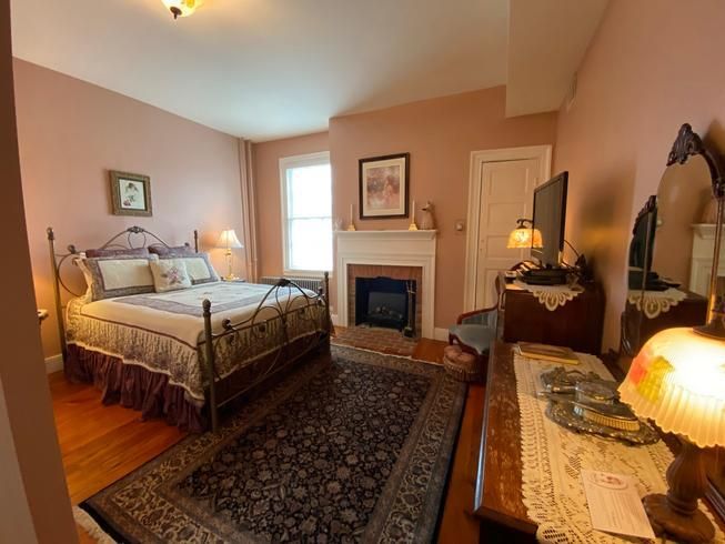 A bedroom with a large bed and a fireplace