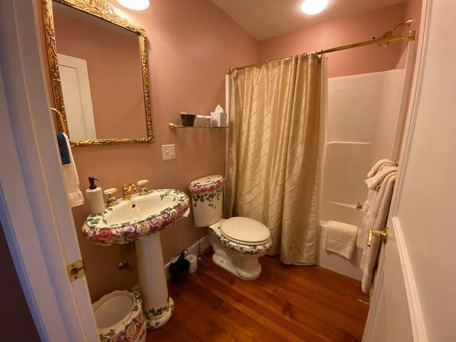 A bathroom with a sink , toilet , shower and mirror.