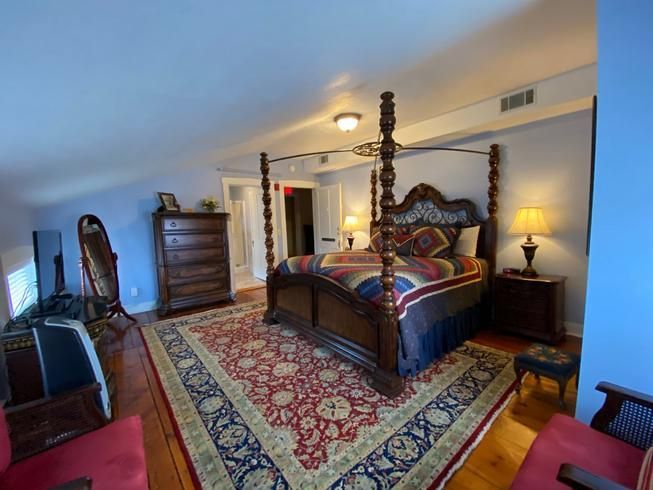 A bedroom with a four poster bed and a rug.