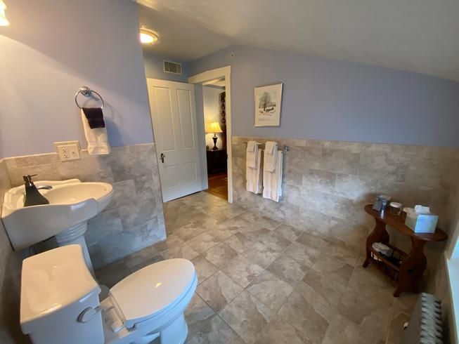 A bathroom with a toilet , sink , and towel rack.