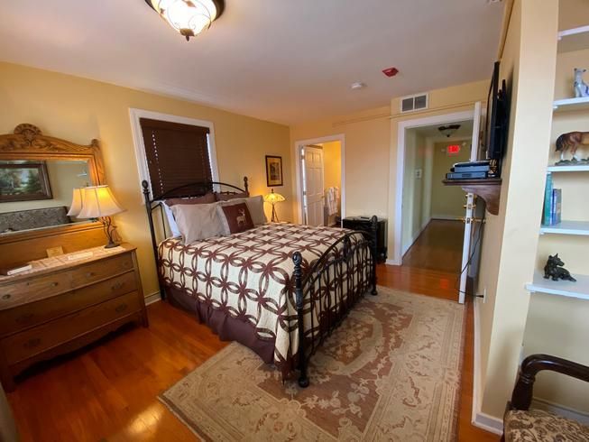 A bedroom with a king size bed , dresser , mirror and rug.