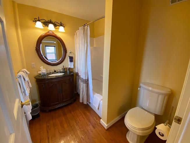 A bathroom with a toilet , sink , mirror and bathtub.